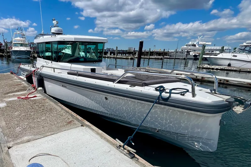 Slide: The Image of 2019 Axopar 28 Cabin boat docked at marina under blue sky. - 2