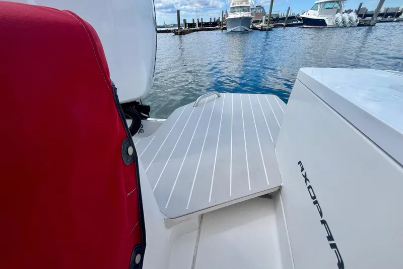 Slide: The Image of 2019 Axopar 28 Cabin boat interior with red seat and dock view. - 21