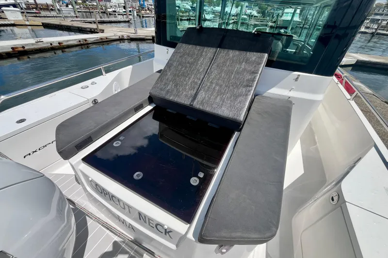Slide: The Image of 2019 Axopar 28 Cabin boat with cushioned seating, docked at a marina. - 22