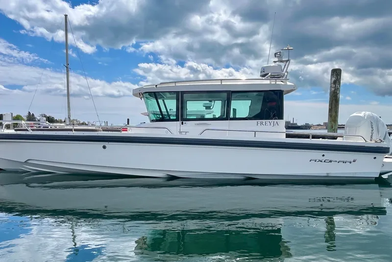 Slide: The Image of 2019 Axopar 28 Cabin boat on calm water under a cloudy sky. - 24