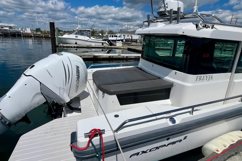 Slide: The Image of 2019 Axopar 28 Cabin boat docked, featuring a Mercury outboard engine. - 3