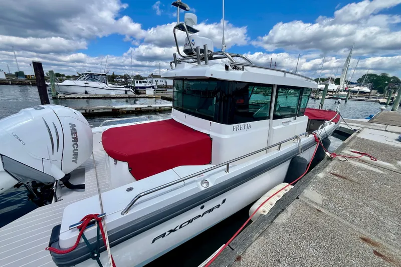 Slide: The Image of 2019 Axopar 28 Cabin boat docked, featuring Mercury engine and red cover. - 4