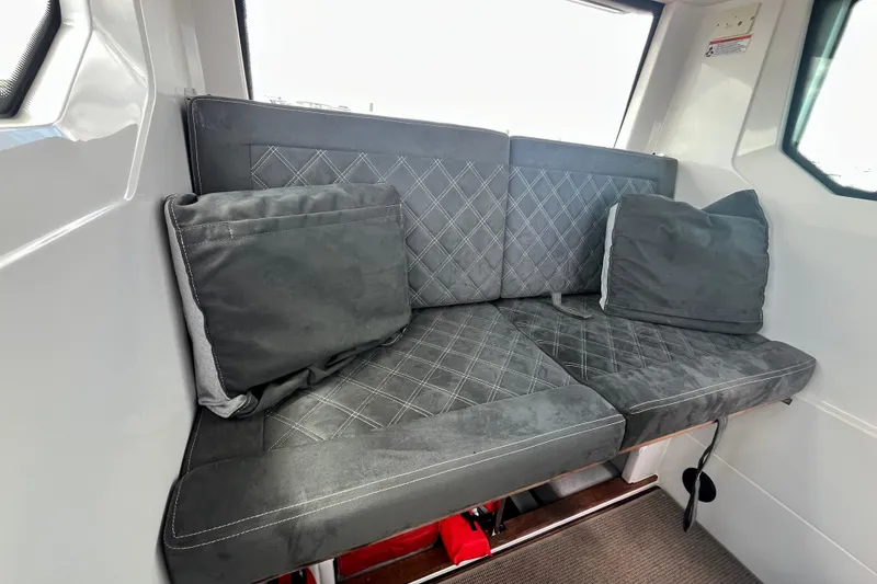 Slide: The Image of Interior seating of 2019 Axopar 28 Cabin with gray cushions and quilted design. - 8