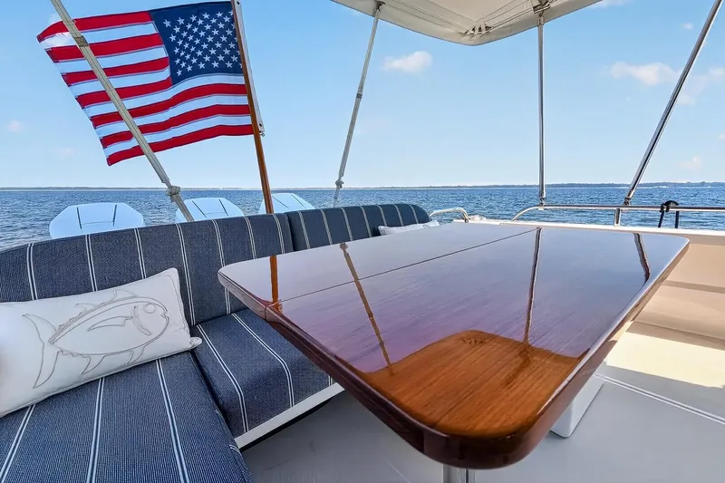 Slide: The Image of 2024 Back Cove 39O yacht deck with American flag and polished wooden table. - 13