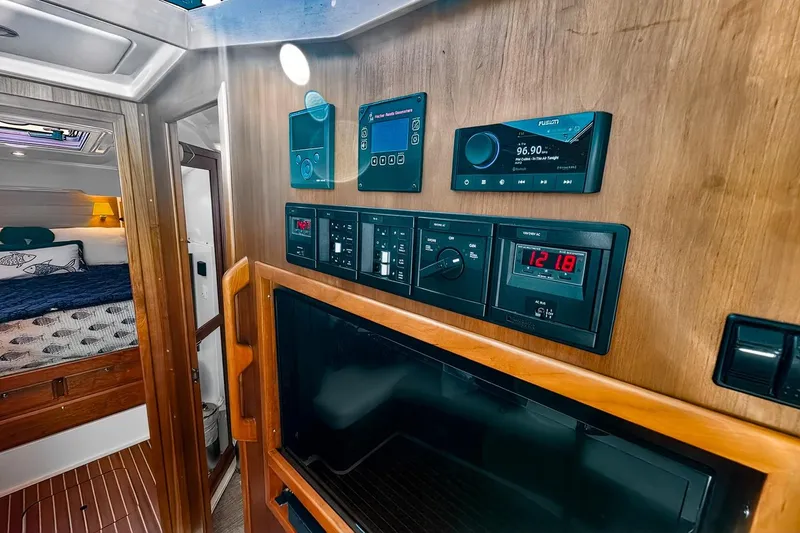 Slide: The Image of 2024 Back Cove 39O yacht lower deck/ seating area with control panels, smart TV, head entrance and companionway to forward stateroom and mid-cabin - 37