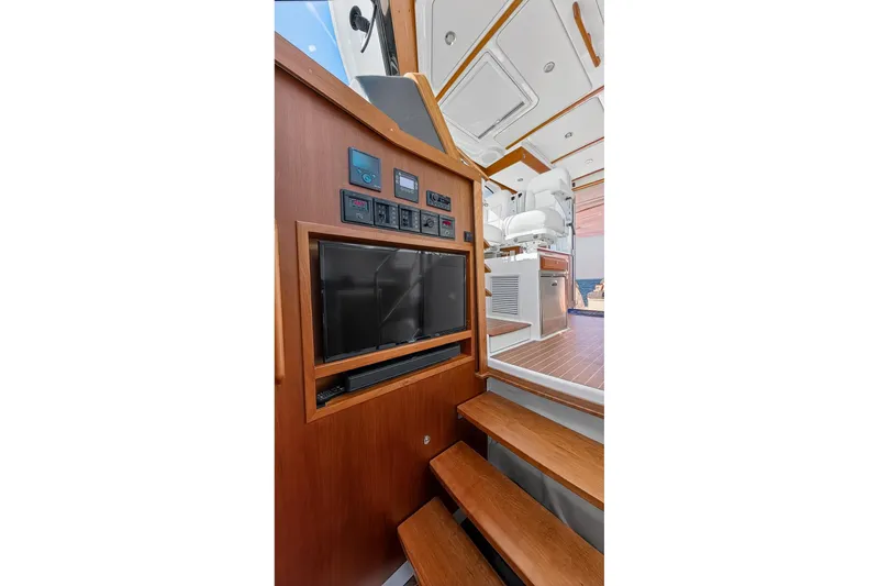 Slide: The Image of 2024 Back Cove 39O yacht interior with wooden stairs, control panel, and seating area. - 38