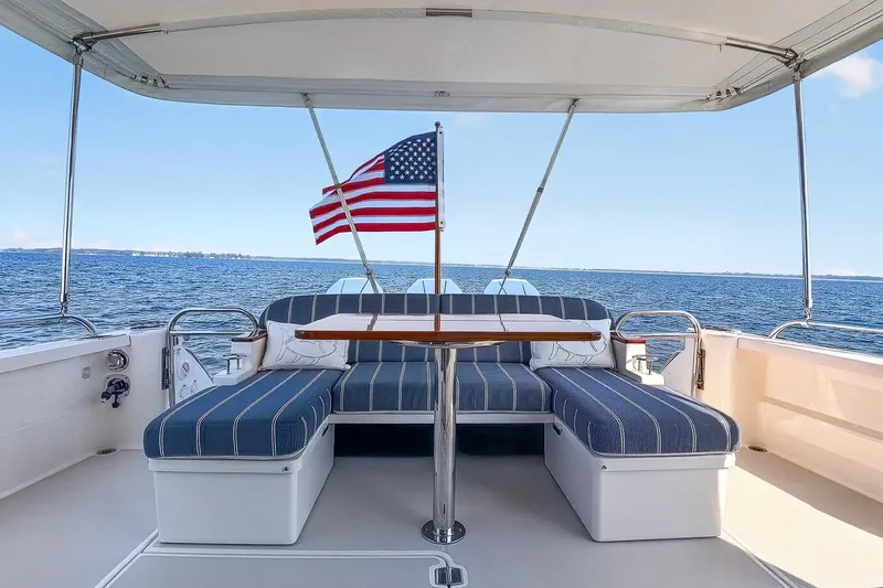 Slide: The Image of 2024 Back Cove 39O yacht deck with seating, table, and American flag on open water. - 7