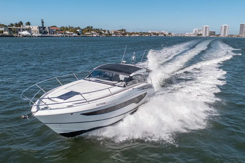 Slide: The Image of 2021 Princess V40 yacht cruising on a sunny day near coastal homes. - 2