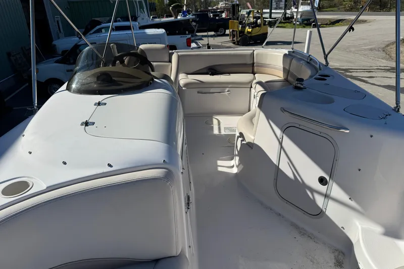 Slide: The Image of 1997 Chaparral 232 Sunesta boat interior with seating and steering wheel, docked outdoors. - 10