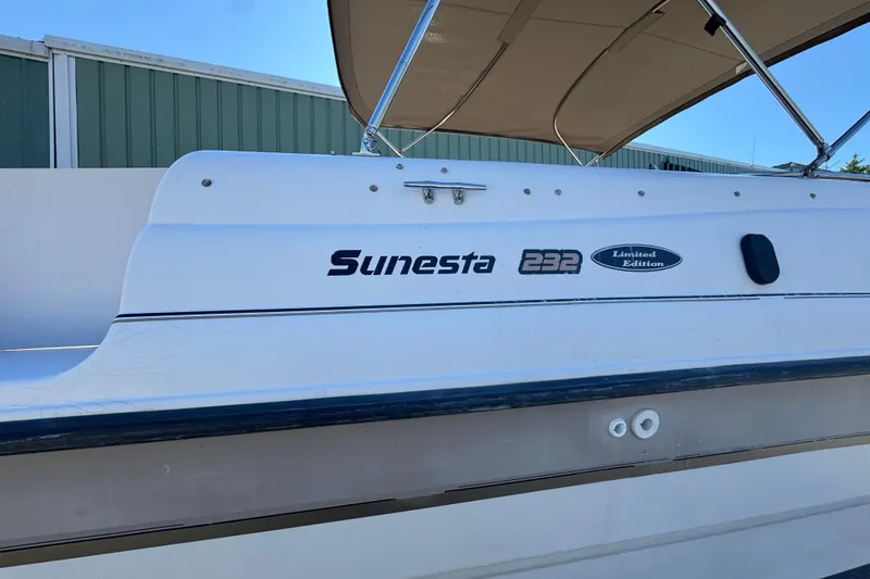 Slide: The Image of 1997 Chaparral 232 Sunesta Limited Edition boat with canopy, docked near a building. - 15