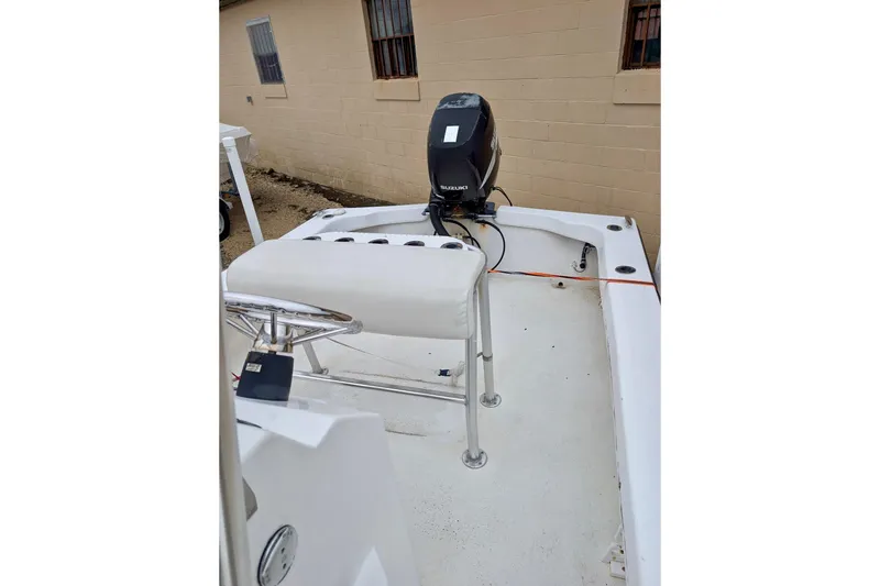 Slide: The Image of 2006 Twin Vee 19 BayCat boat with Suzuki outboard motor, parked near a beige building. - 10