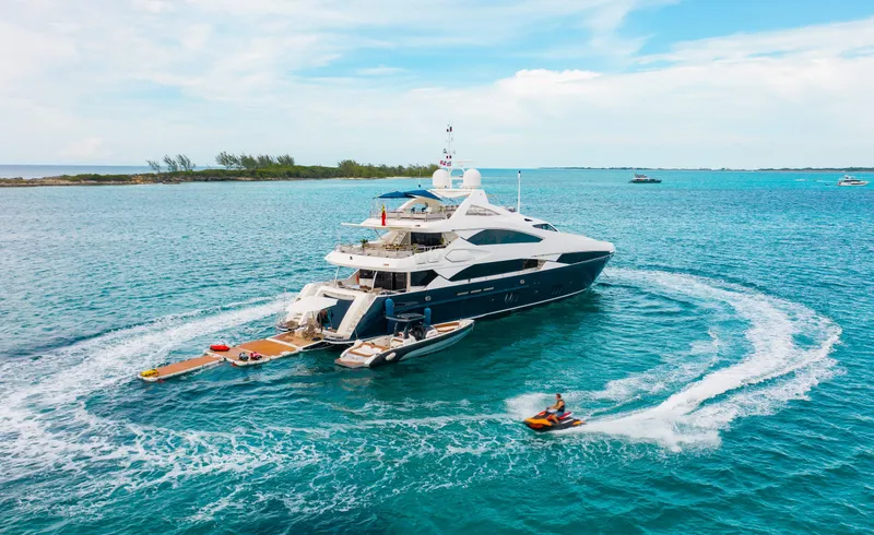 Slide: The Image of Luxury 2009 Sunseeker 121 yacht cruising in clear blue waters with jet ski nearby. - 2
