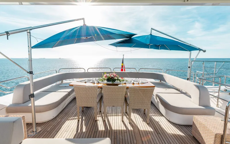 Slide: The Image of Luxury Sunseeker 121 yacht deck with dining area, blue umbrellas, and ocean view, 2009 model. - 8