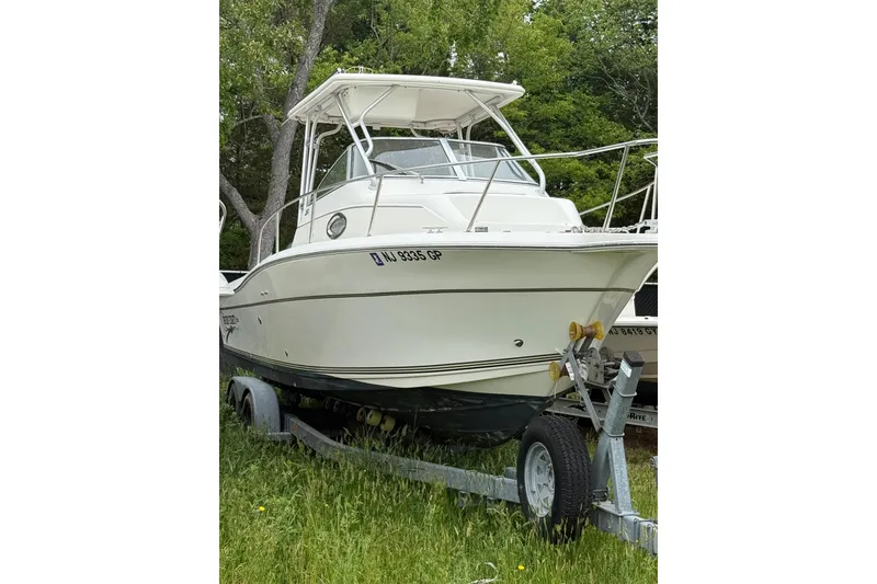 The Image of 2002 Sports-Craft 261 boat on trailer, parked on grass with trees in background. - 1