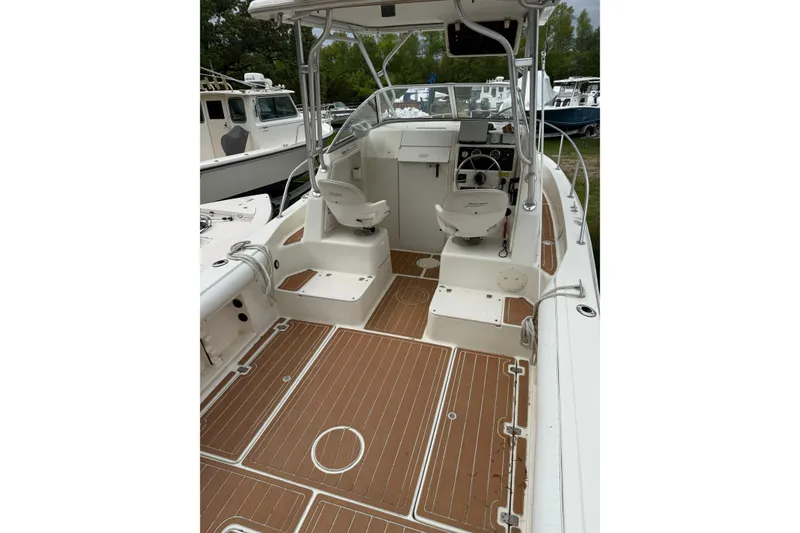 Slide: The Image of 2002 Sports-Craft 261 boat interior with seating, steering wheel, and wooden deck. - 2