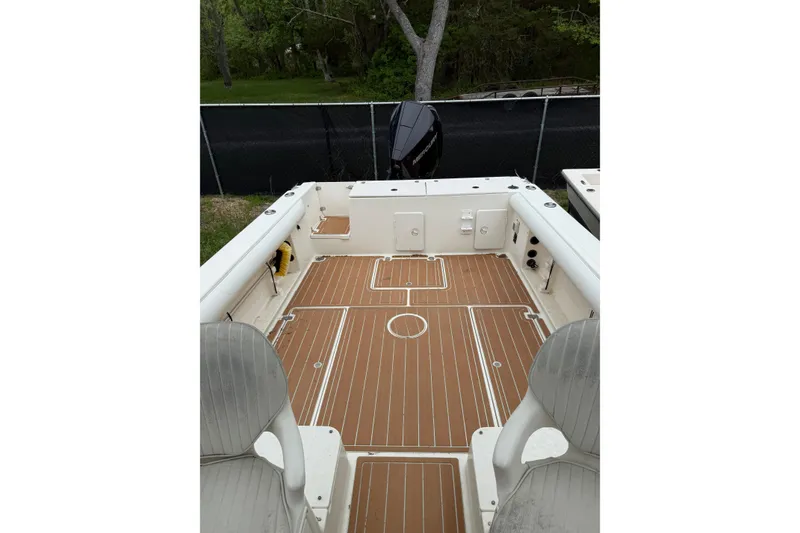 Slide: The Image of 2002 Sports-Craft 261 boat interior with teak flooring and seating, docked outdoors. - 5
