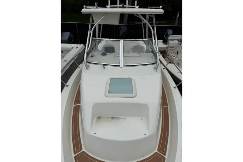 Slide: The Image of 2002 Sports-Craft 261 boat with white deck and windshield, docked alongside other boats. - 8