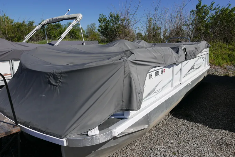Slide: The Image of 2010 JC Neptoon 21TT pontoon boat covered with a gray tarp, parked outdoors. - 12