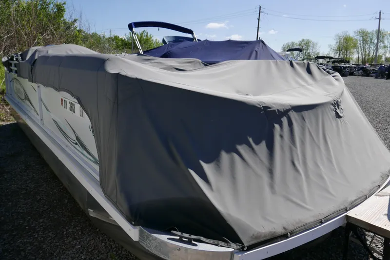 Slide: The Image of 2010 JC Neptoon 21TT pontoon boat covered with a protective tarp in a storage area. - 13