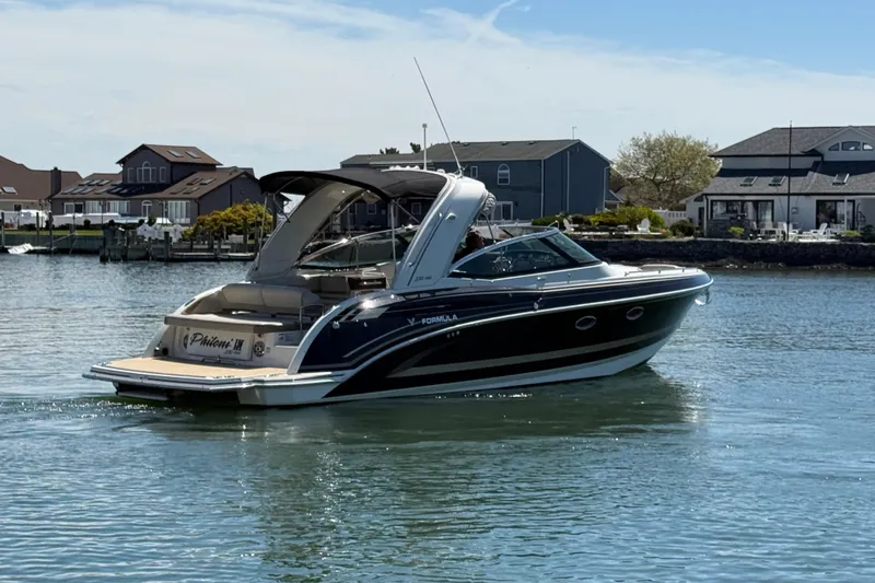 Slide: The Image of 2015 Formula 330 Crossover Bowrider boat cruising near waterfront homes. - 10