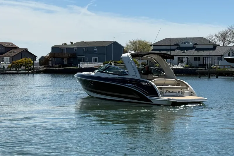 Slide: The Image of 2015 Formula 330 Crossover Bowrider cruising on a calm waterfront near houses. - 11