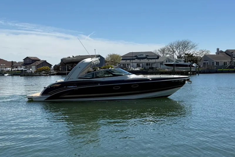 The Image of 2015 Formula 330 Crossover Bowrider on calm water near residential docks. - 8