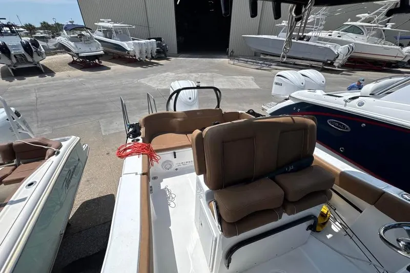 Slide: The Image of 2023 Sea Hunt Ultra 239 SE boat interior with brown seating at a marina. - 13