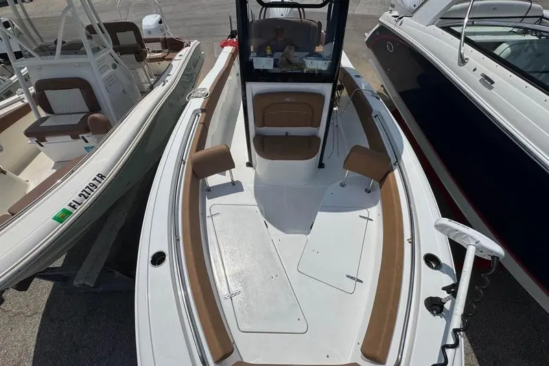 Slide: The Image of 2023 Sea Hunt Ultra 239 SE boat interior with seating and console, docked alongside other boats. - 7