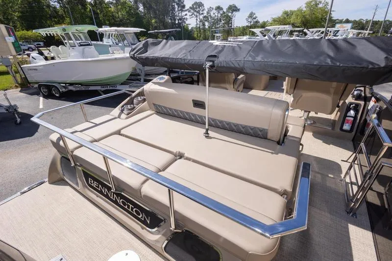 Slide: The Image of 2023 Bennington R23 Swingback pontoon boat with beige seating and canopy, parked outdoors. - 18