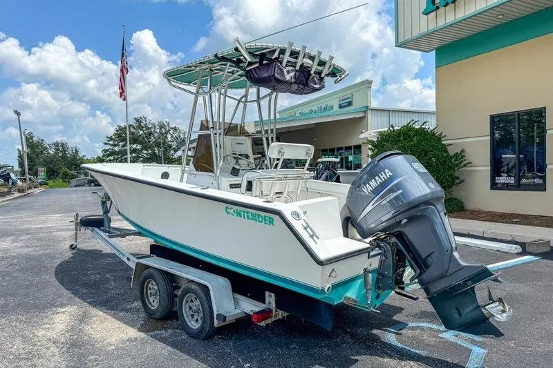 Slide: The Image of 1997 Contender 21 Open boat on trailer with Yamaha outboard motor, parked outside a building. - 2