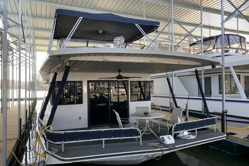 The Image of 1985 Sumerset 18x81 houseboat docked under covered marina, featuring outdoor seating area. - 0