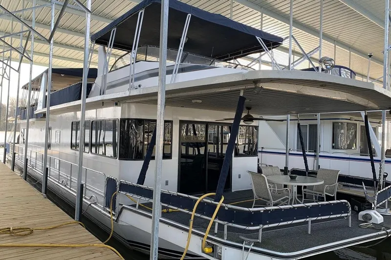 Slide: The Image of 1985 Sumerset 18x81 houseboat docked, featuring spacious deck and covered seating area. - 3