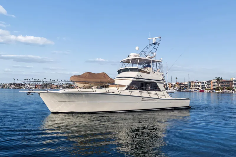Slide: The Image of 1988 Viking 48 Convertible yacht on calm water, with coastal buildings in the background. - 2