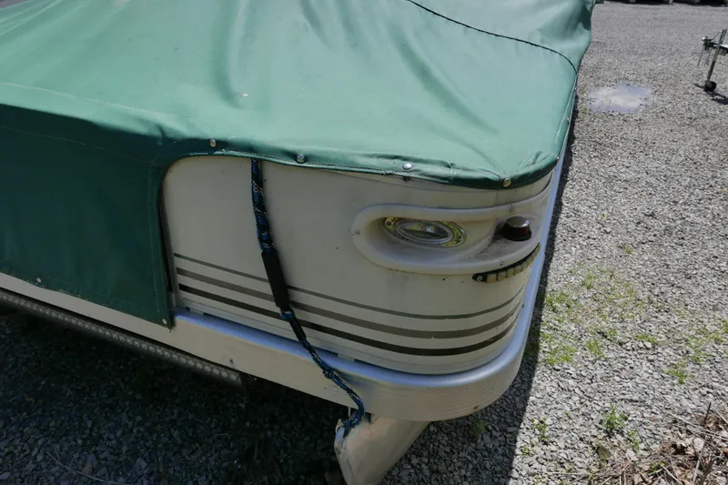 Slide: The Image of 2005 Bennington 257FS boat with green cover on gravel surface. - 12