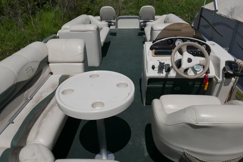 Slide: The Image of 2005 Bennington 257FS pontoon boat interior with white seating and steering console. - 9