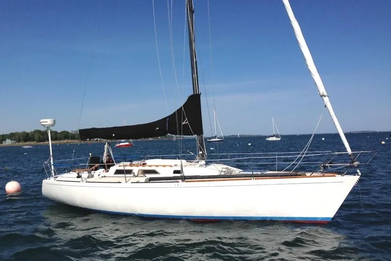 The Image of 1986 Express 37 sailboat on calm water, clear sky background. - 0
