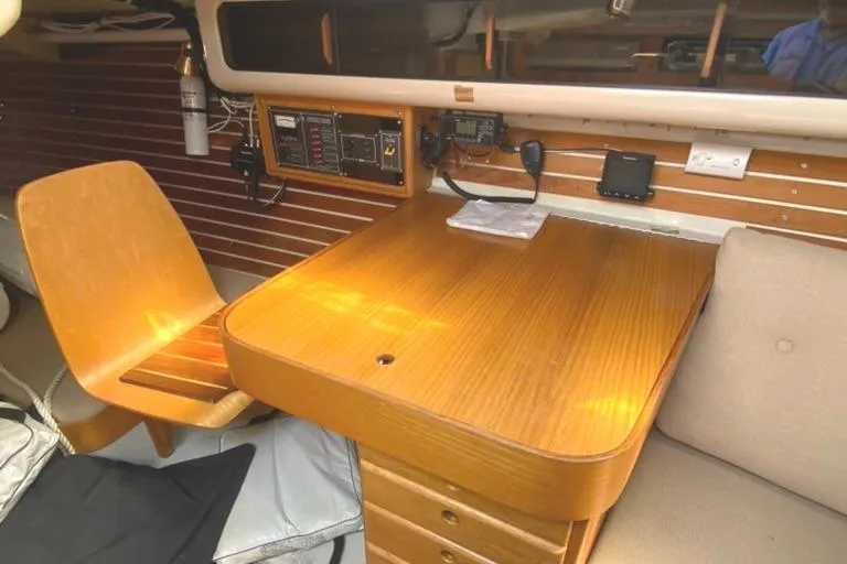 Slide: The Image of 1986 Express 37 sailboat interior with wooden table, chair, and navigation equipment. - 28