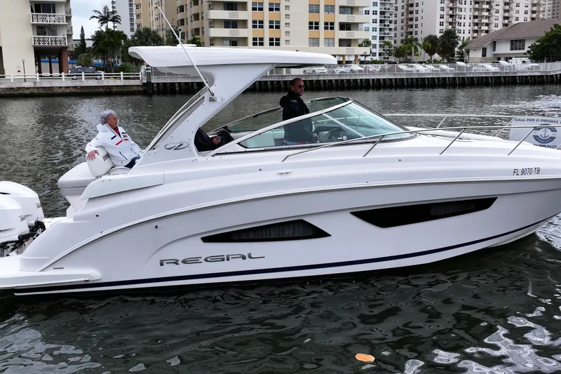 Slide: The Image of 2021 Regal 33 XO boat cruising on a canal with two passengers onboard. - 2