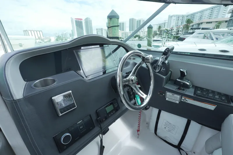 Slide: The Image of 2021 Regal 33 XO boat helm with modern controls and cityscape background. - 8
