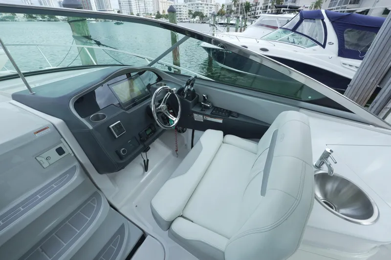 Slide: The Image of 2021 Regal 33 XO boat cockpit with steering wheel and sink, docked in marina. - 9