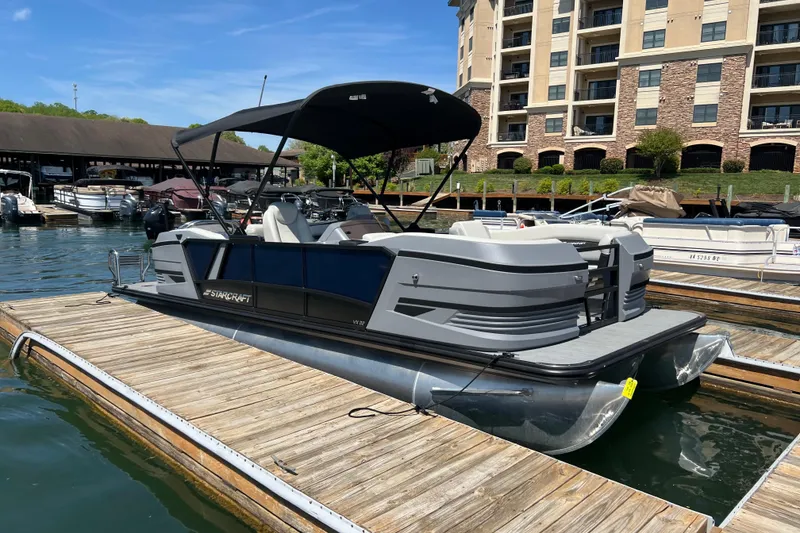 The Image of 2026 Starcraft VX 22 R DH pontoon boat docked at a marina under a clear blue sky. - 0