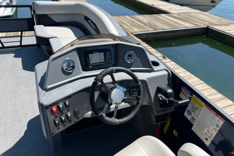 Slide: The Image of 2026 Starcraft VX 22 R DH boat dashboard with steering wheel and controls at dock. - 14