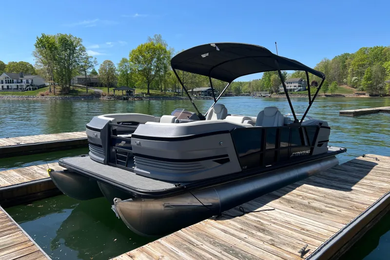 Slide: The Image of 2026 Starcraft VX 22 R DH pontoon boat docked on a serene lake under clear skies. - 3