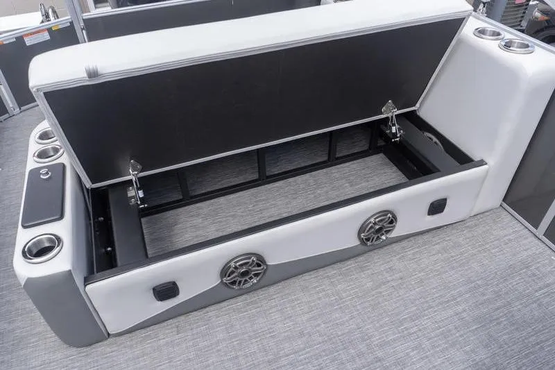 Slide: The Image of Open storage compartment on 2026 SunCatcher Elite 326 SL boat with cup holders and speakers. - 22