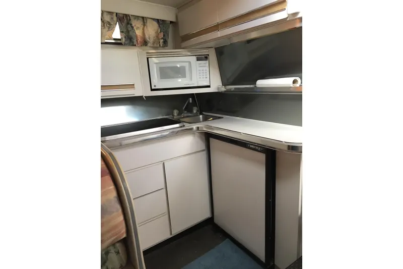 Slide: The Image of Compact kitchen area in a 1989 Wellcraft 3200 St. Tropez boat, featuring a microwave and sink. - 4
