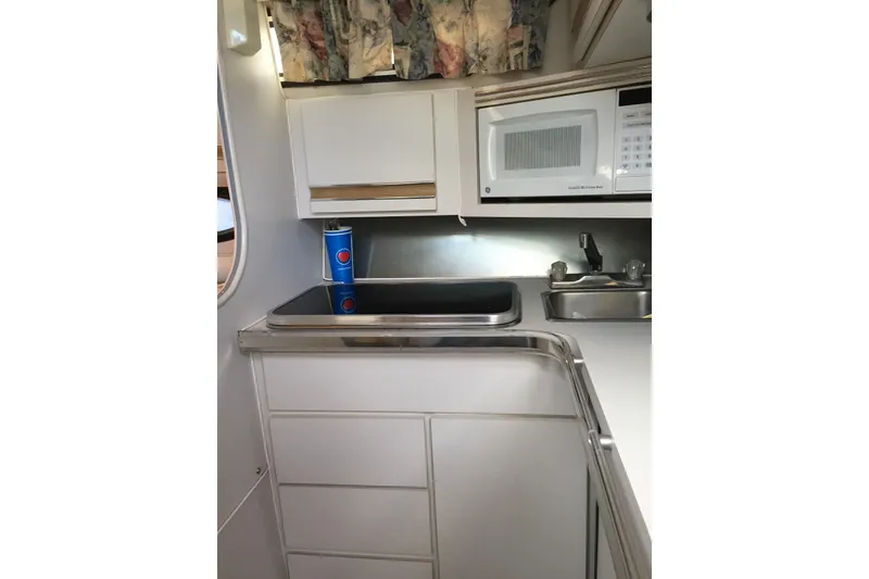 Slide: The Image of 1989 Wellcraft 3200 St. Tropez boat kitchen with sink, microwave, and storage cabinets. - 5