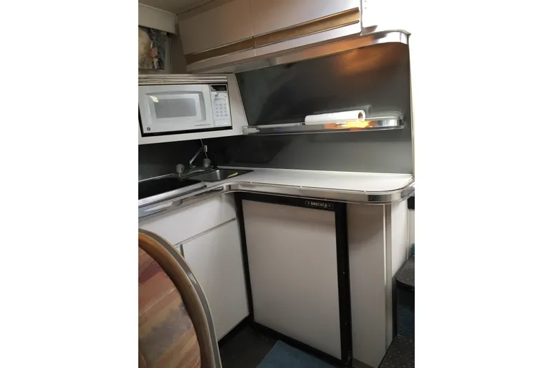 Slide: The Image of 1989 Wellcraft 3200 St. Tropez boat kitchen with microwave, sink, and compact fridge. - 6