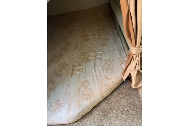 Slide: The Image of 2007 Rinker Fiesta Vee 250 cabin interior with patterned mattress and beige curtain. - 11