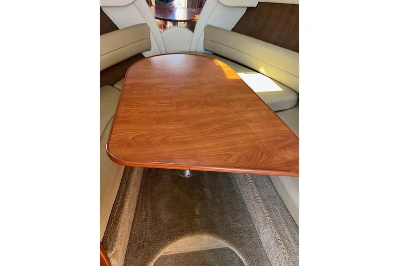 Slide: The Image of 2007 Rinker Fiesta Vee 250 cabin interior with wooden table and cushioned seating. - 5