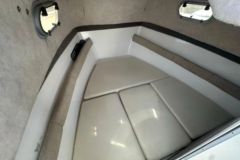 Slide: The Image of 2004 Sea Pro 220 Walk Around cabin interior with cushioned seating and portholes. - 18